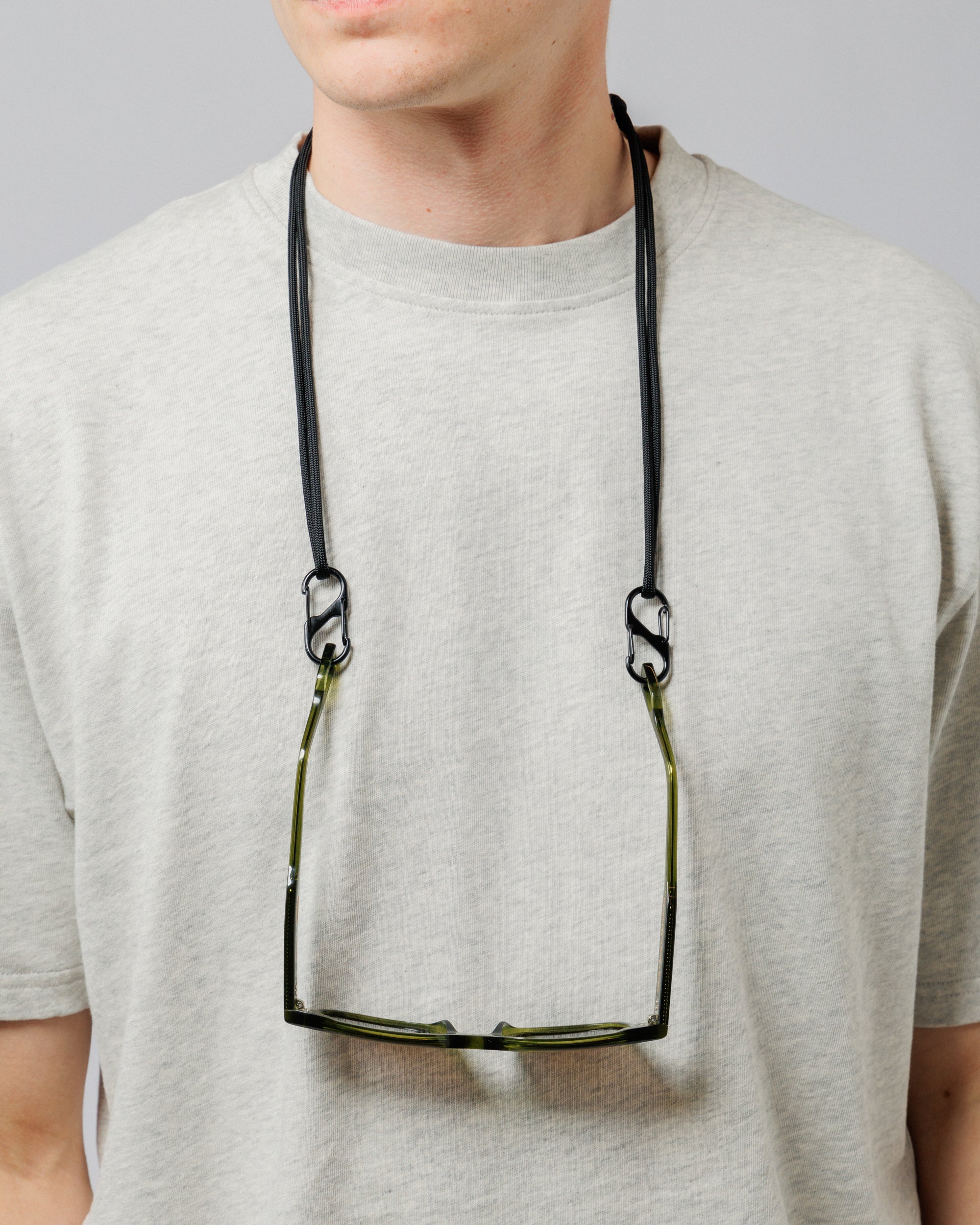 Solaris Sunglasses in khaki hanging from paracord sunglasses strap worn around neck